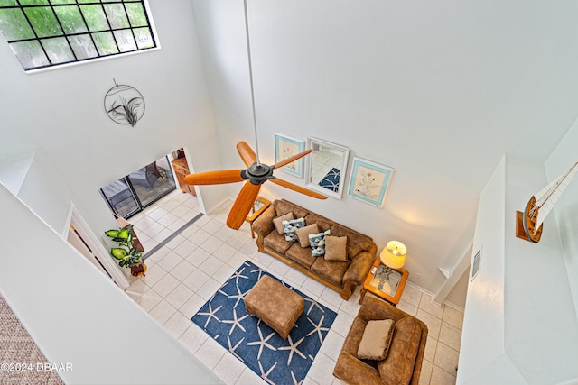 living room with a towering ceiling, ceiling fan, and tile patterned floors