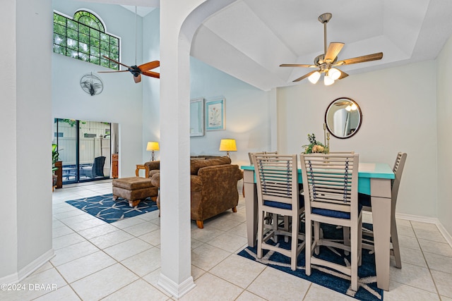 tiled dining space with ceiling fan, plenty of natural light, and a tray ceiling