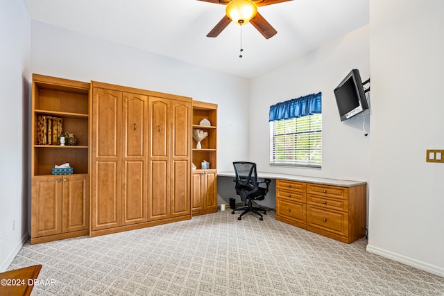 carpeted office with built in desk and ceiling fan