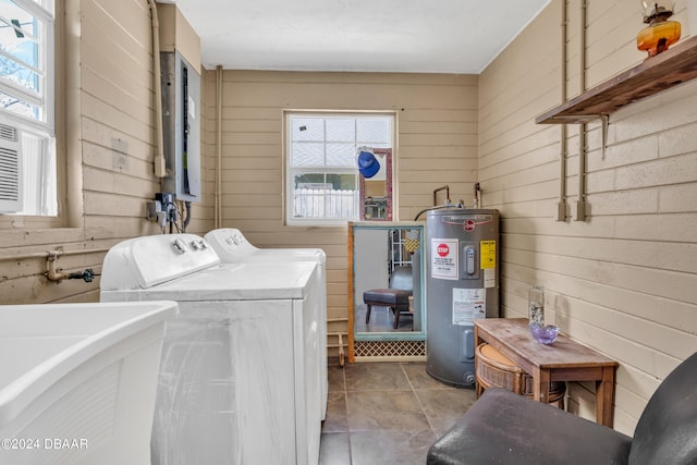 washroom with light tile patterned floors, wooden walls, sink, electric water heater, and washer and dryer