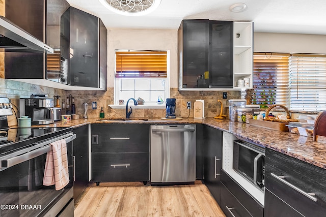 kitchen with dark stone counters, light wood-type flooring, appliances with stainless steel finishes, and sink