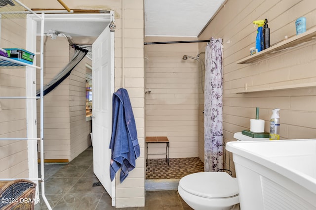 bathroom featuring walk in shower, wooden walls, and toilet