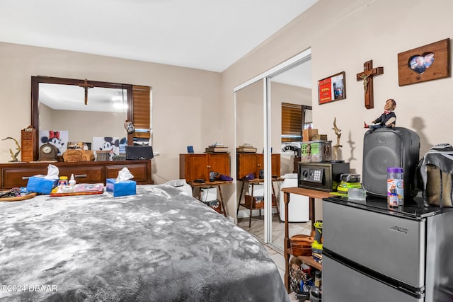 bedroom with stainless steel refrigerator and a closet