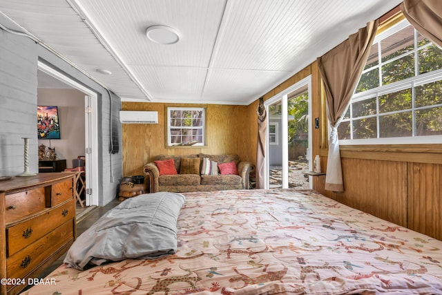 bedroom featuring access to exterior, an AC wall unit, wood walls, and multiple windows