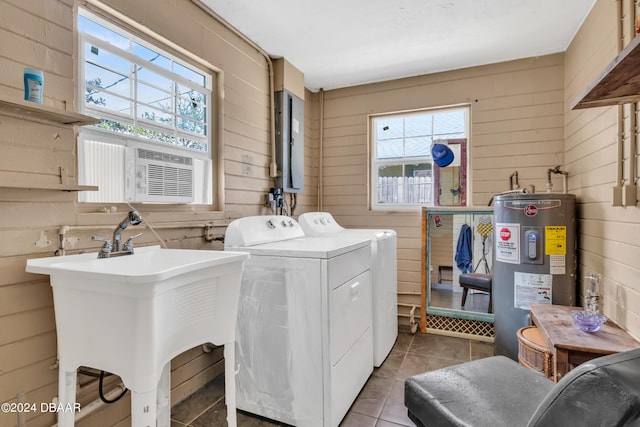 clothes washing area featuring electric water heater, light tile patterned flooring, wooden walls, and washer and dryer