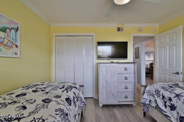 bedroom with ceiling fan, crown molding, light hardwood / wood-style flooring, electric panel, and a closet