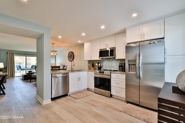 kitchen featuring backsplash, white cabinets, sink, light wood-type flooring, and appliances with stainless steel finishes