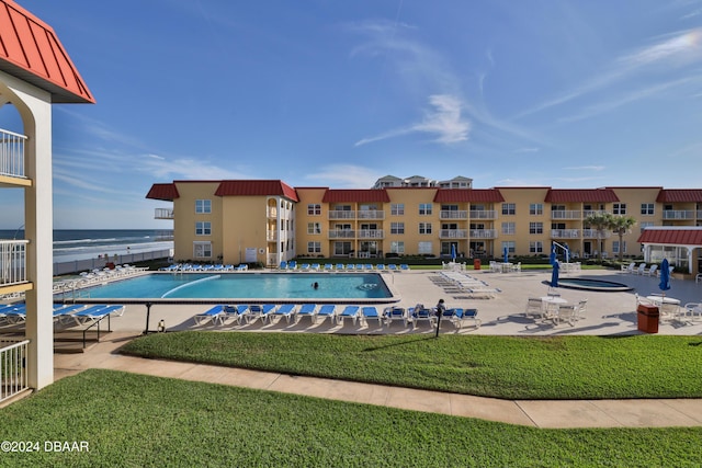 view of swimming pool with a patio area, a yard, and a water view