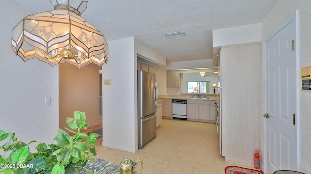 kitchen featuring visible vents, white dishwasher, light countertops, a sink, and freestanding refrigerator