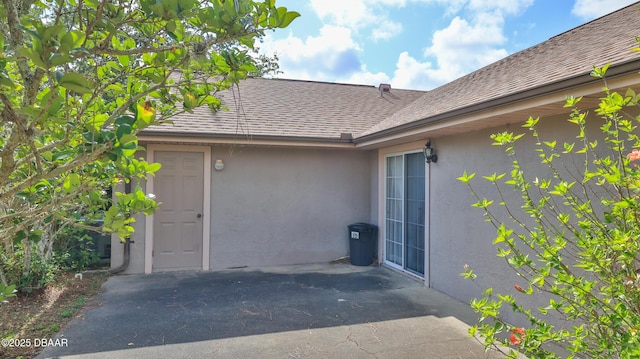 exterior space featuring a shingled roof and stucco siding