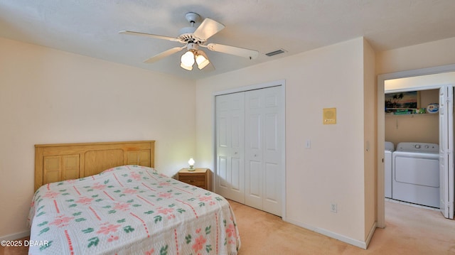 bedroom featuring washer and dryer, baseboards, light colored carpet, and a closet