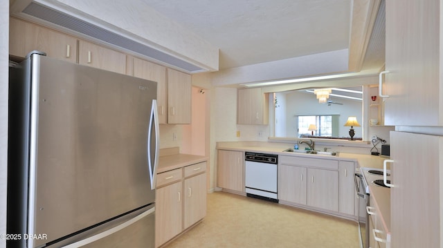 kitchen featuring light countertops, appliances with stainless steel finishes, a sink, and light brown cabinets