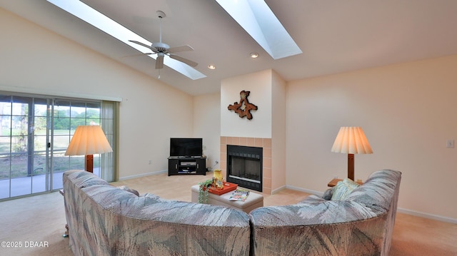 living room featuring a skylight, baseboards, a tiled fireplace, and light colored carpet