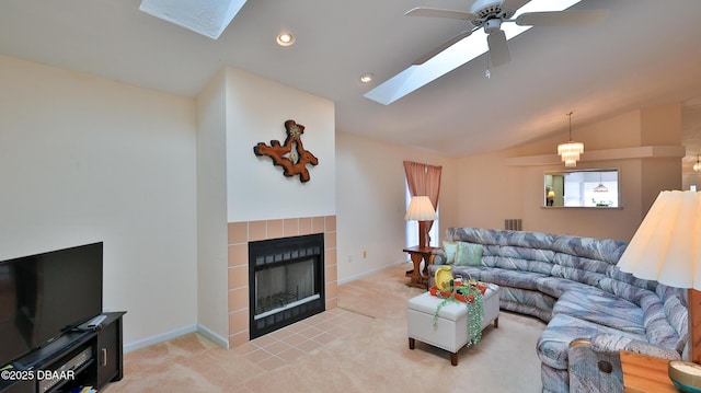living room featuring a ceiling fan, light carpet, lofted ceiling with skylight, and a tile fireplace