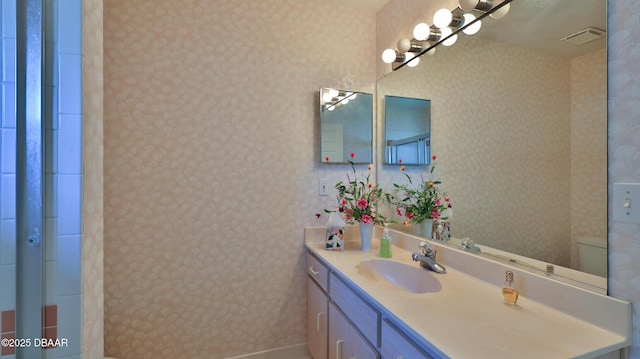 bathroom with wallpapered walls, visible vents, and vanity