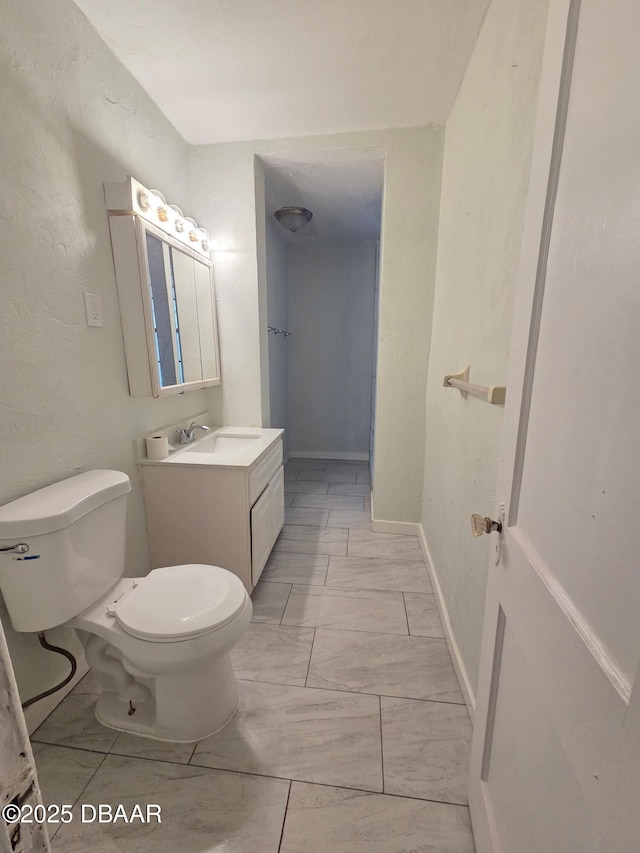 229 S Adams St, Daytona Beach, FL 32117 - bathroom with marble look tile flooring, toilet, vanity, and baseboards