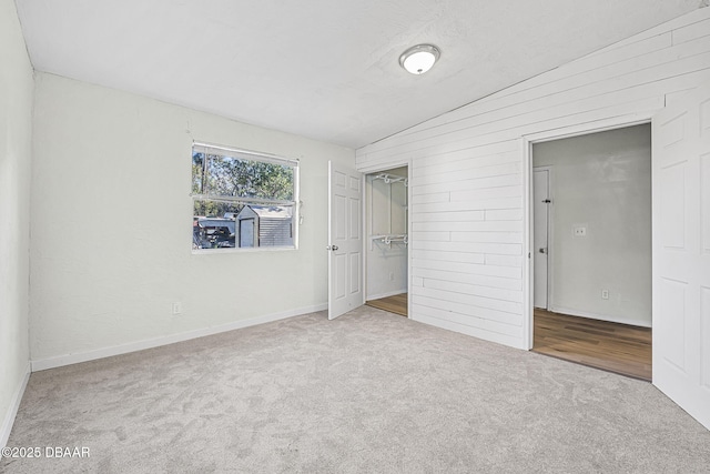 229 S Adams St, Daytona Beach, FL 32117 - unfurnished bedroom with lofted ceiling, carpet floors, baseboards, a closet, and wood walls