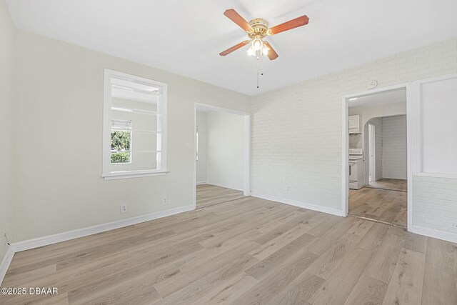 229 S Adams St, Daytona Beach, FL 32117 - unfurnished bedroom with brick wall, light wood-style flooring, baseboards, arched walkways, and connected bathroom