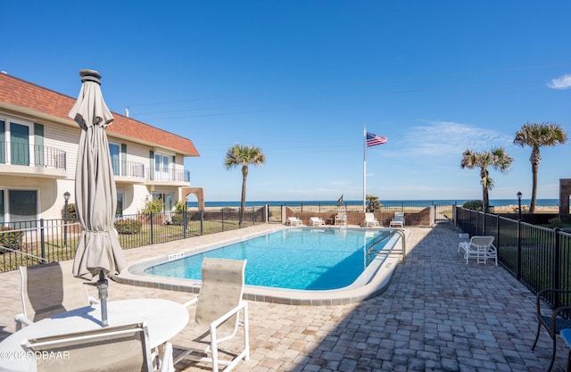 view of pool featuring a water view and a patio