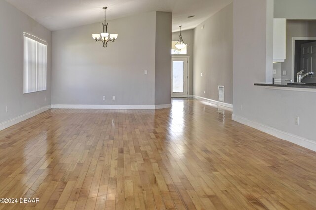 empty room featuring sink, a chandelier, and light wood-type flooring