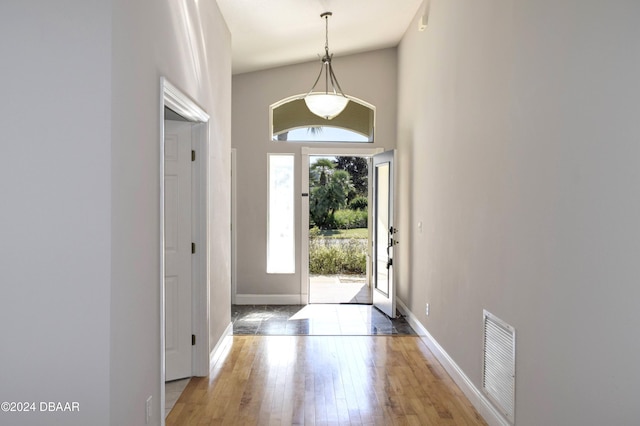 foyer entrance with high vaulted ceiling, wood-type flooring, and a wealth of natural light