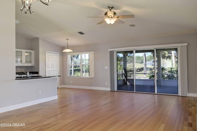 unfurnished living room with light hardwood / wood-style floors, vaulted ceiling, a healthy amount of sunlight, and sink