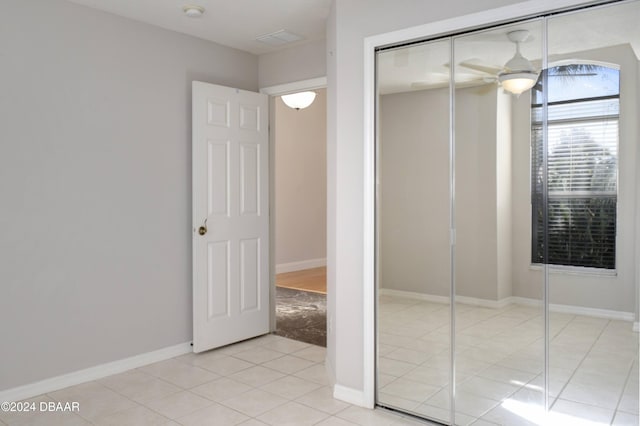 unfurnished bedroom featuring light tile patterned flooring, a closet, and ceiling fan