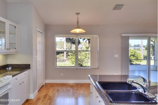 kitchen with sink, white range with electric cooktop, decorative light fixtures, white cabinets, and light wood-type flooring