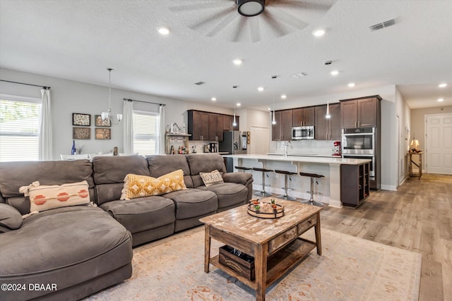 living room featuring a textured ceiling, light hardwood / wood-style flooring, and ceiling fan