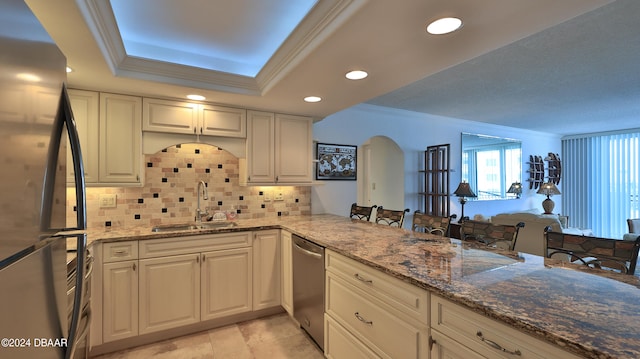 kitchen with stainless steel appliances, sink, kitchen peninsula, stone counters, and decorative backsplash