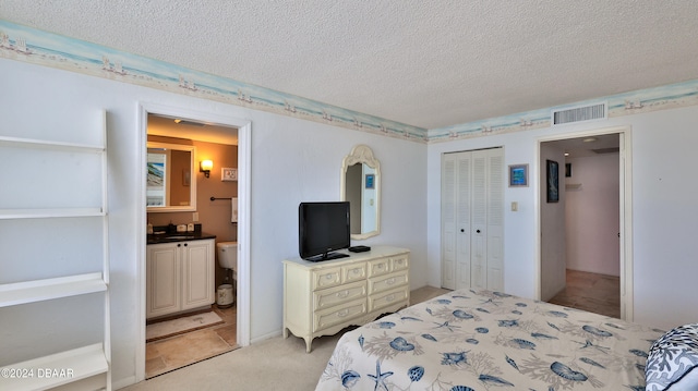 carpeted bedroom with a textured ceiling and ensuite bath