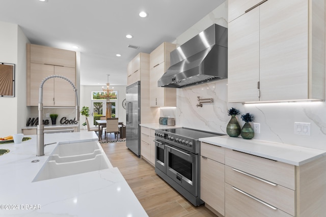 kitchen featuring light brown cabinets, light hardwood / wood-style floors, wall chimney exhaust hood, and high quality appliances