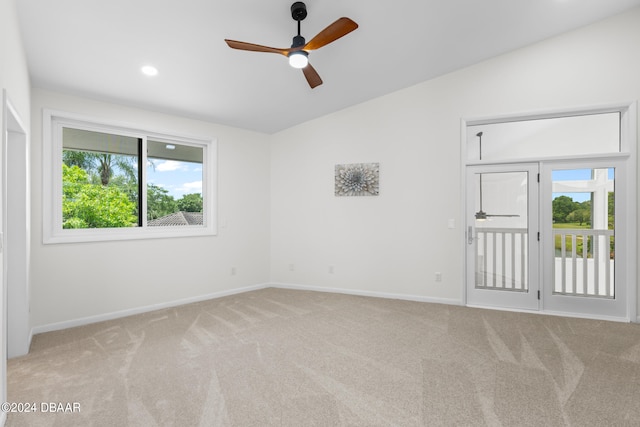 carpeted spare room featuring ceiling fan, lofted ceiling, and a healthy amount of sunlight