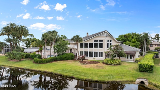 back of property featuring a water view and a lawn