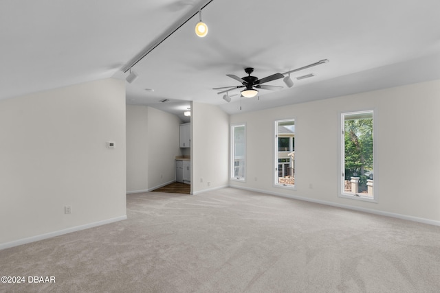 unfurnished living room featuring track lighting, light carpet, ceiling fan, and vaulted ceiling