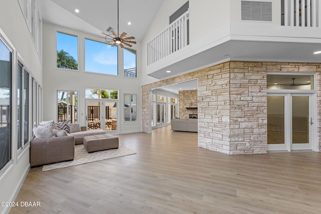 unfurnished living room featuring ceiling fan, a healthy amount of sunlight, light wood-type flooring, and high vaulted ceiling