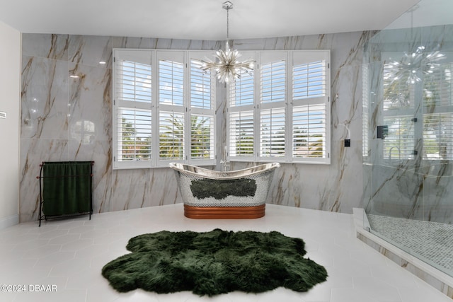 bathroom with an inviting chandelier, tile patterned floors, and a tile shower