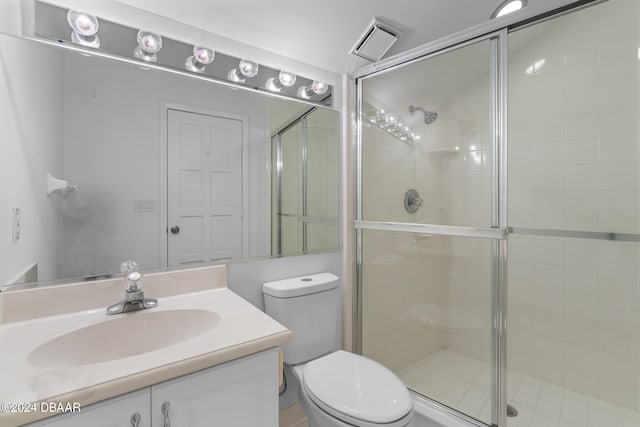 bathroom featuring toilet, vanity, and a shower with shower door