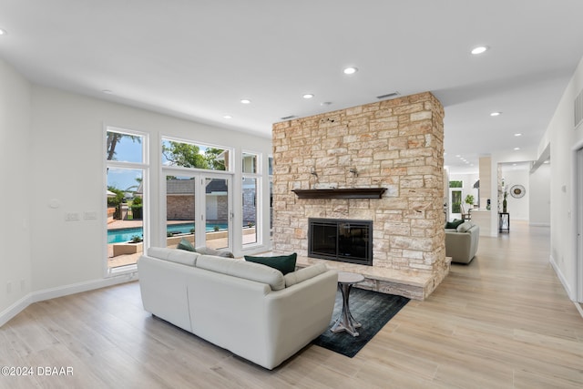 living room featuring a stone fireplace and light hardwood / wood-style floors