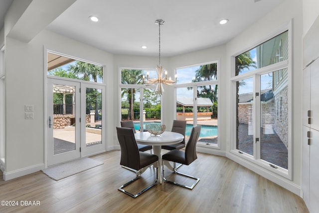 dining area with light wood-type flooring and a notable chandelier