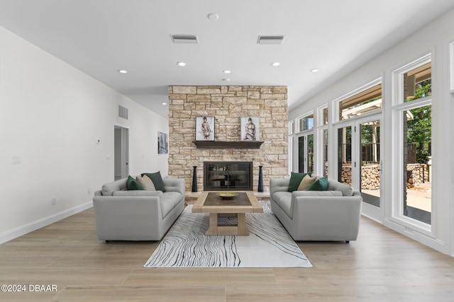 living room with a stone fireplace and light hardwood / wood-style flooring