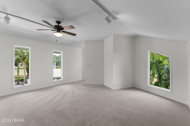 carpeted spare room featuring a wealth of natural light, track lighting, vaulted ceiling, and ceiling fan