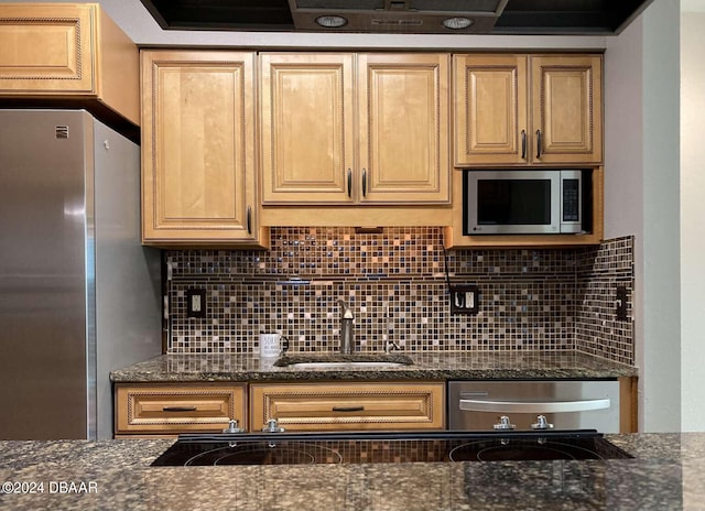 kitchen with dark stone countertops, sink, backsplash, and appliances with stainless steel finishes