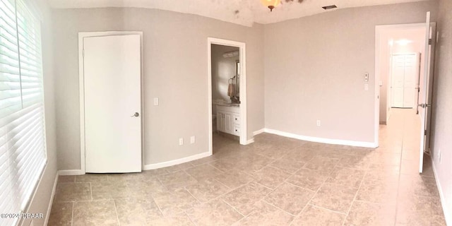 1401 S Palmetto Ave Unit 214, Daytona Beach, FL 32114 - unfurnished bedroom featuring baseboards, connected bathroom, and light tile patterned flooring