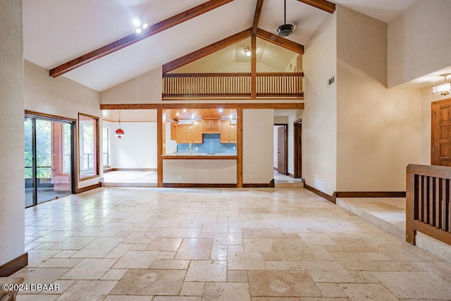 unfurnished living room with french doors, beam ceiling, sink, and high vaulted ceiling