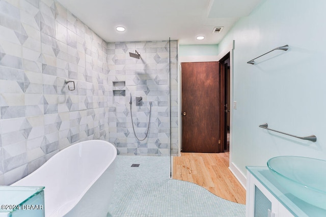 bathroom featuring wood-type flooring, vanity, and plus walk in shower