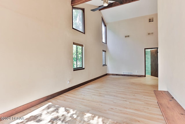 unfurnished room with high vaulted ceiling, light hardwood / wood-style floors, and beamed ceiling