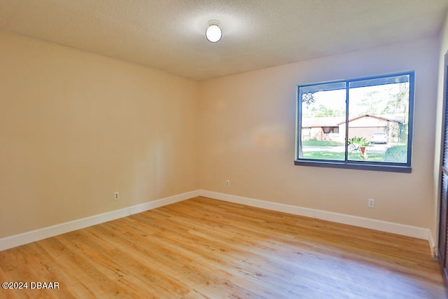 spare room with a textured ceiling and light hardwood / wood-style floors