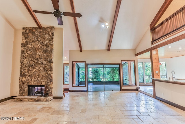 unfurnished living room with a fireplace, high vaulted ceiling, sink, beamed ceiling, and ceiling fan