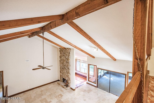 additional living space with ceiling fan, a stone fireplace, and vaulted ceiling with beams